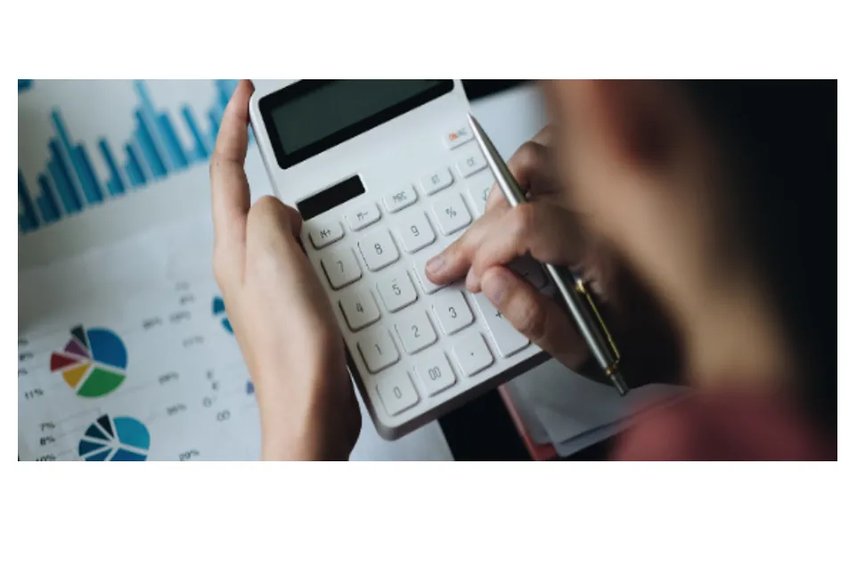 Hands using a calculator over printed financial charts