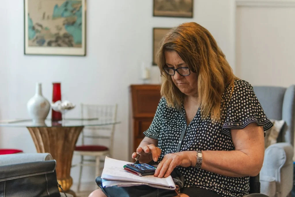 Woman reviewing her finances with a calculator and papers at home