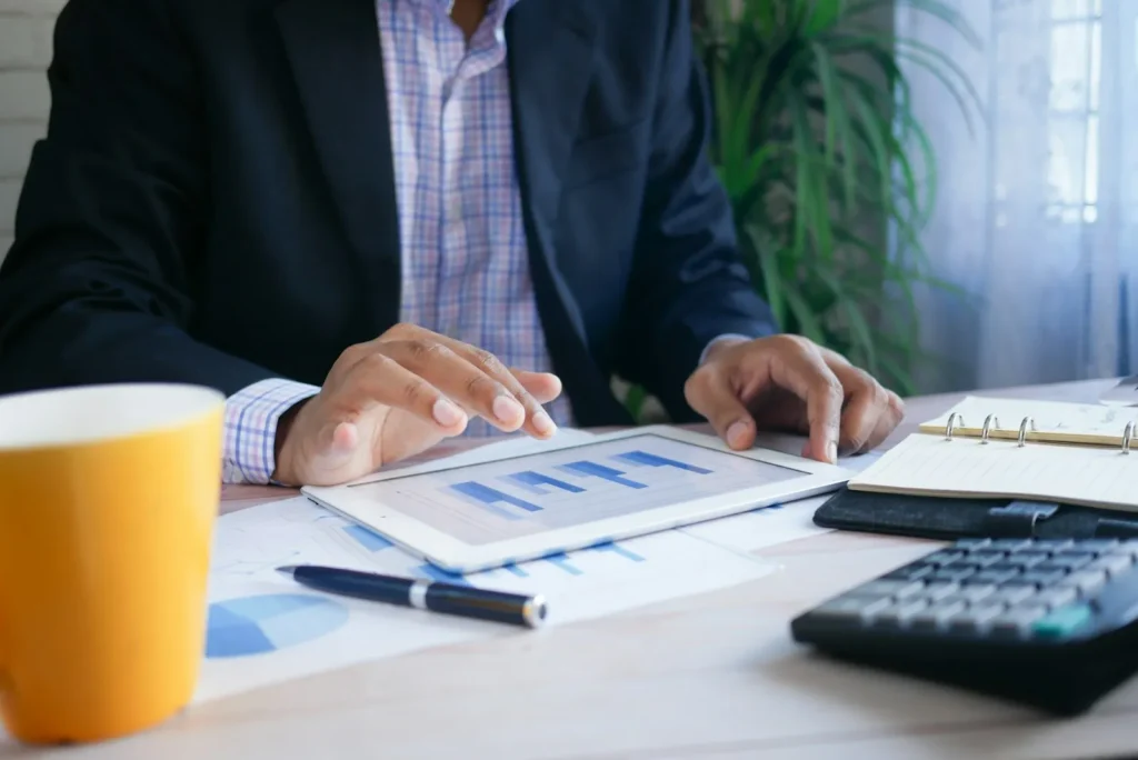 Professional reviewing financial charts on a tablet beside a calculator