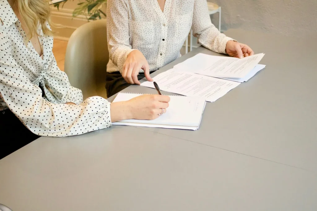 Two women reviewing and signing documents at a table
