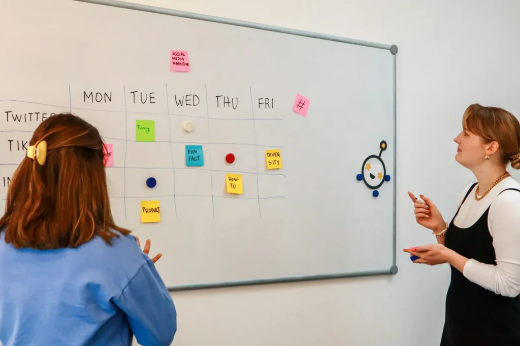 Two women planning with sticky notes on a whiteboard