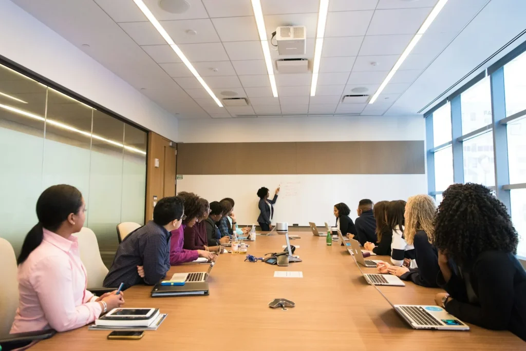 Team around a conference table listening to a woman present