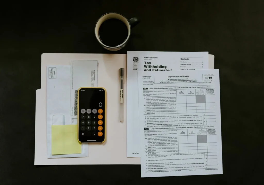Tax forms, a pen and a phone calculator on a desk